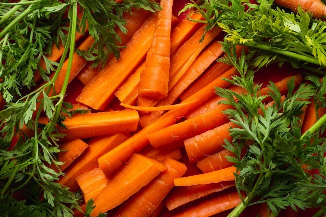Orange morötter med gröna blastdelar, fotograferade tätt uppifrån